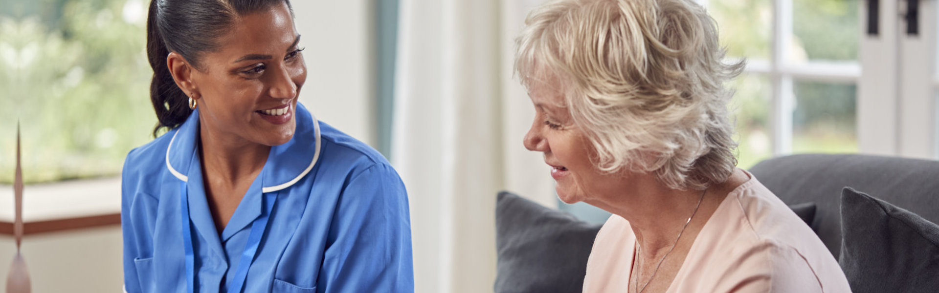 Senior Woman At Home Talking To Female Nurse